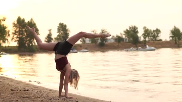 Jeune fille blonde fait handstand sur la plage au ralenti. — Video