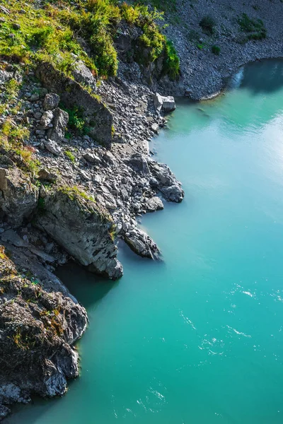 Rocks going into the turquoise waters of the river Katun. Mountain Altai, Southern Siberia, Russia