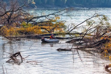 OB Nehri, Verkh-Suzun, Suzun ilçe, Novosibirsk bölgesi, Batı Sibirya, Rusya Federasyonu-22, Eylül 2018: Nehri üzerinde su dolu snags arasında bir şişme tekne balıkçılık balıkçı