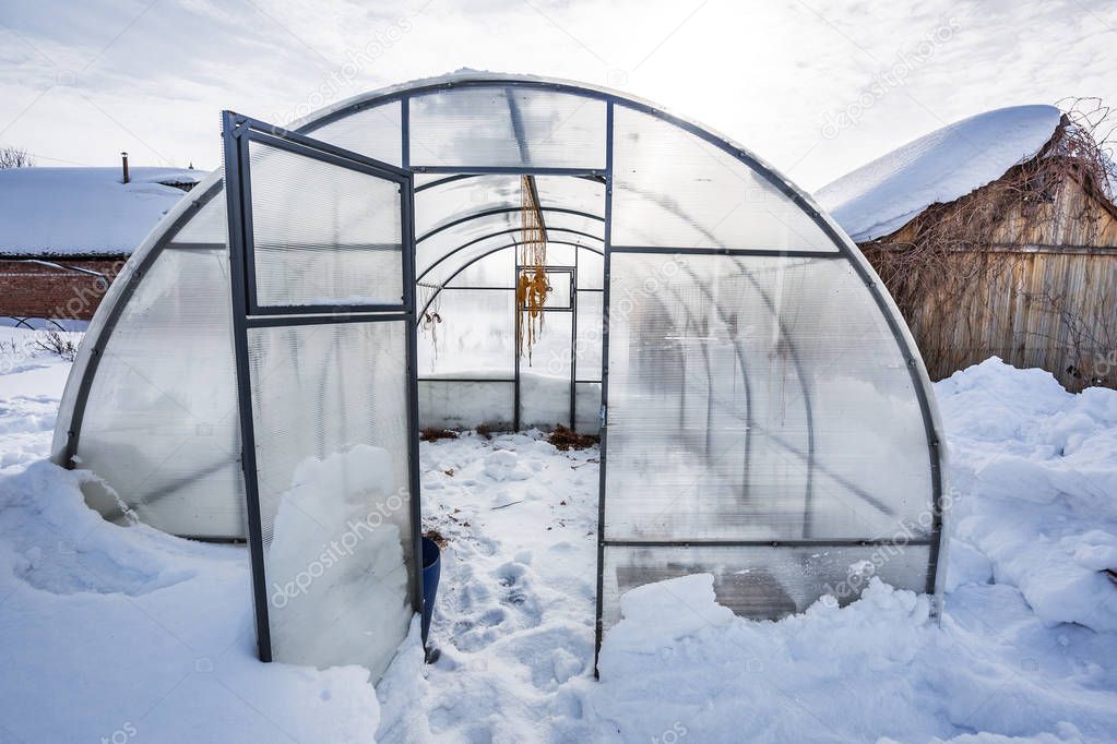Snow removal from the greenhouse polycarbonate in the country. Berdsk, Novosibirsk region, Western Siberia, Russia