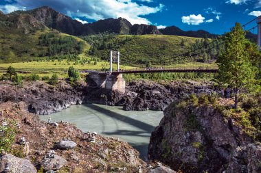 Chemalsky bölgesi, Altai Cumhuriyeti, Güney Sibirya, Rusya-19 Ağustos 2020: Oroktoysky otomobil asma köprüsü Katun nehri üzerinde dağlar ve taş piramitlerle çevrili