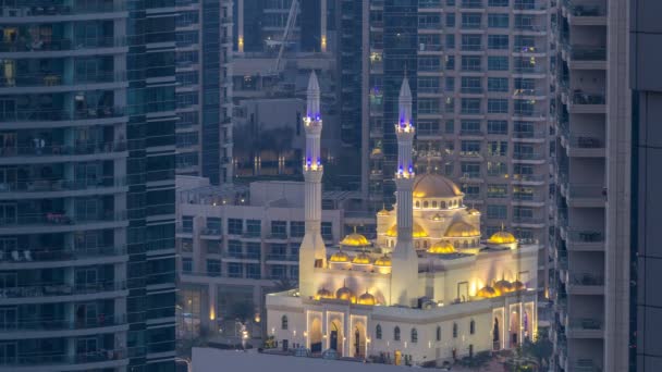Al Raheem moskee tussen wolkenkrabbers dag naar nacht timelapse op de wandeling van de jachthaven in Dubai Marina, Dubai, Verenigde Arabische Emiraten. — Stockvideo