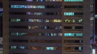 Windows çok katlı binanın içinde aydınlatma ve insanlar timelapse içinde hareketli çelik ve cam. Modern ofis gökdelenler Dubai Hava görünümünü. Yukarı kaydır