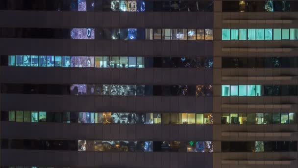 Windows av flera våningar byggnad av glas och stål belysning inuti och flytta människor inom timelapse — Stockvideo