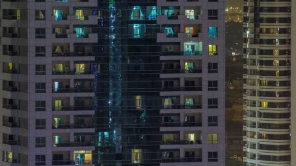Окна многоэтажного здания из стекла и стали освещения внутри и перемещения людей в течение времени — стоковое видео