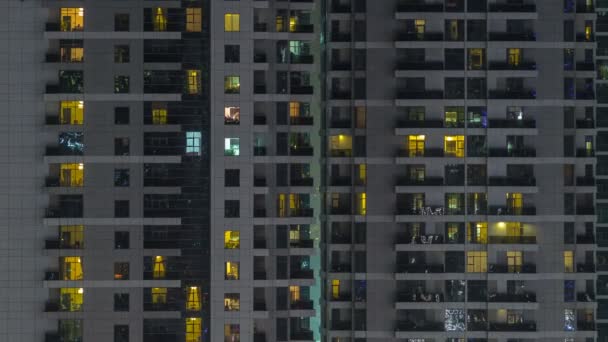 Windows av flera våningar byggnad av glas och stål belysning inuti och flytta människor inom timelapse — Stockvideo