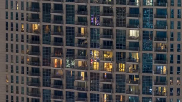 Windows av flera våningar byggnad av glas och stål belysning inuti och flytta människor inom timelapse — Stockvideo