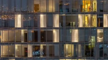 Yanıp sönen ve windows çok katlı binanın cam ve çelik iç aydınlatma ve insanlar timelapse içinde hareketli yanıp sönen. Dubai merkezinde modern konut gökdelenlerin havadan görünümü