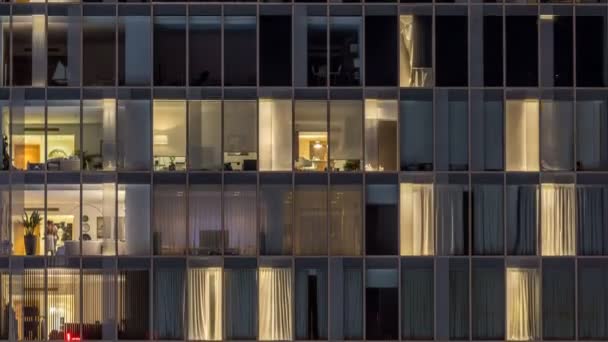 Windows av flera våningar byggnad av glas och stål belysning inuti och flytta människor inom timelapse — Stockvideo