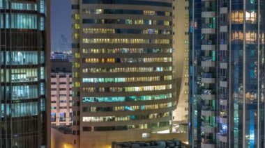 Windows çok katlı binanın içinde aydınlatma ve insanlar timelapse içinde hareketli çelik ve cam. Modern konut ve ofis gökdelen içinde Dubai deira hava görünümünü. Yukarı kaydır