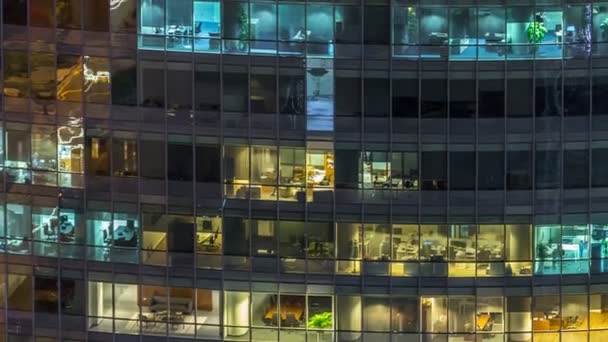 Windows av flera våningar byggnad av glas och stål belysning inuti och flytta människor inom timelapse — Stockvideo