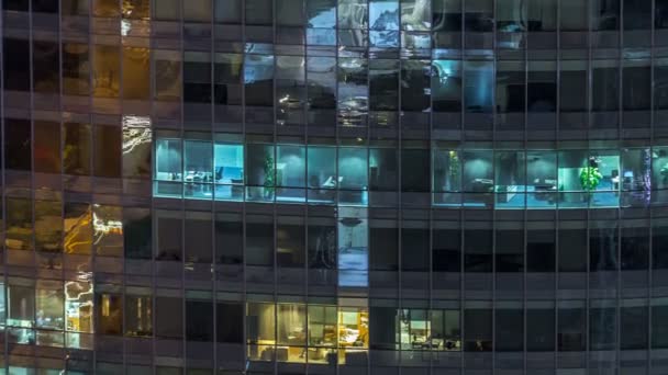 Windows av flera våningar byggnad av glas och stål belysning inuti och flytta människor inom timelapse — Stockvideo