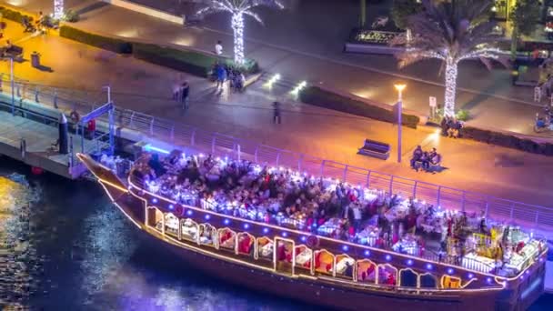 Barco turístico de madera en Dubai Marina Bay iluminado por la noche timelapse — Vídeo de stock