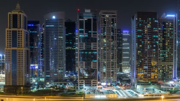 Letecký pohled na Jumeirah lakes towers mrakodrapy během všech noční timelapse s provozem na bulváru sheikh zayed road. — Stock video