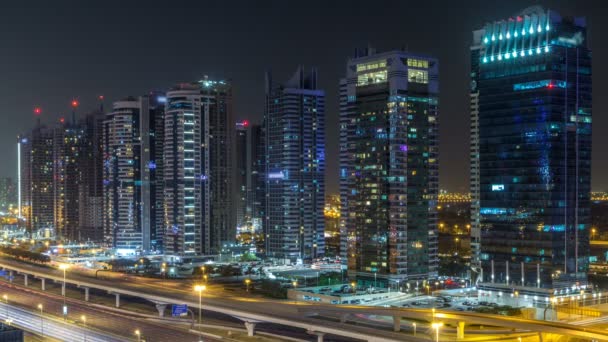 Vista aérea de las torres de los lagos de Jumeirah rascacielos durante toda la noche timelapse con el tráfico en sheikh zayed carretera . — Vídeo de stock