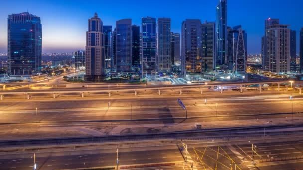 Aerial view of Jumeirah lakes towers skyscrapers night to day timelapse with traffic on sheikh zayed road. — Stock Video