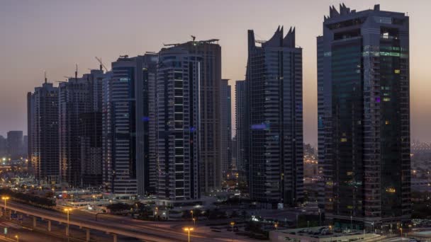 Vista aérea de las torres de los lagos de Jumeirah rascacielos noche a día timelapse con el tráfico en la carretera sheikh zayed . — Vídeo de stock