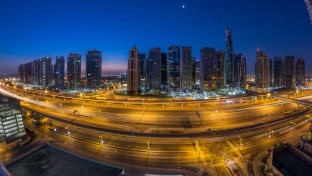 Flygfoto över Jumeirah lakes towers skyskrapor natt till dag timelapse med trafik på sheikh zayed road. — Stockvideo