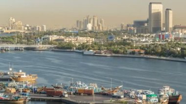 Dubai creek manzara timelapse tekneler ve gemi limanda ve gün batımı sırasında arka planda modern binalar