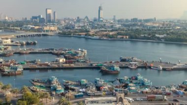 Dubai creek manzara timelapse tekneler ve gemi limanda ve gün batımı sırasında arka planda modern binalar