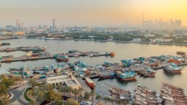 Dubai creek manzara timelapse tekneler ve gemi limanda ve gün batımı sırasında arka planda modern binalar
