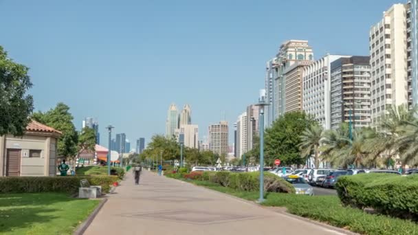 Corniche boulevard beach park along the coastline in Abu Dhabi timelapse with skyscrapers on background. — Stock Video