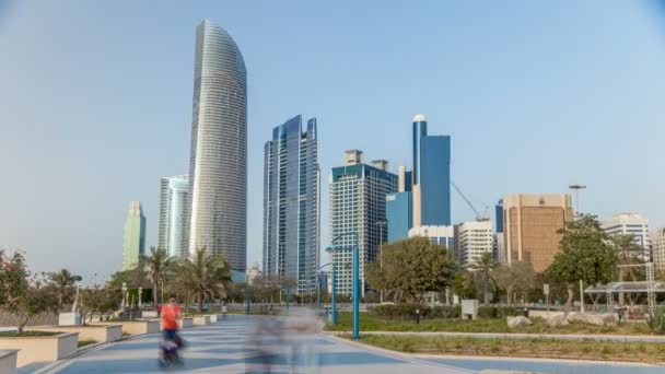 Abu Dabi 'deki sahil şeridi boyunca uzanan Corniche Bulvarı plajı parkında arka planda gökdelenler var.. — Stok video