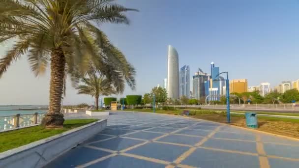 Corniche boulevard beach park a lo largo de la costa en Abu Dhabi timelapse hiperlapso con rascacielos en el fondo. — Vídeos de Stock