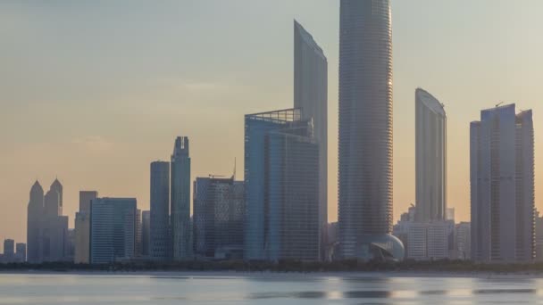 Skyline von Abu Dhabi mit Wolkenkratzern nach Sonnenaufgang im Zeitraffer mit Wasserreflexion — Stockvideo