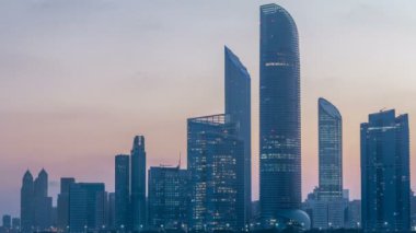 Abu Dabi şehri, gün doğmadan gökdelenlerle gökdelenlerle kaplandı. Gece gündüz su yansımasıyla birlikte.
