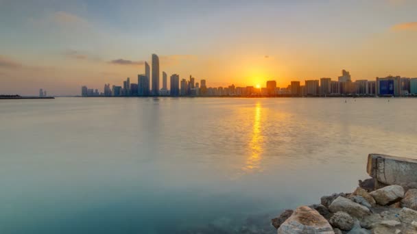 Horizonte de la ciudad de Abu Dhabi en la hora del amanecer con timelapse reflexión sobre el agua. — Vídeo de stock