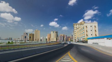 Ajman Cityscape köprü mavi bulutlu gökyüzü timelapse ile bir gün yolda trafik ile. Ajman Emirliği Ajman, Birleşik Arap Emirlikleri başkentidir. 4k