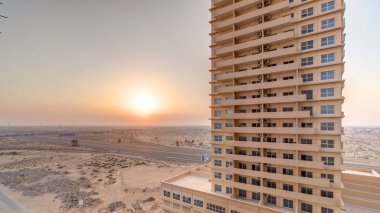 Dubai Havalimanı'na gelen çatı timelapse binalar ve karayolu ile Ajman citiscape Körfezi'nin su yansıması ile gün batımı. Ajman Emirliği Ajman, Birleşik Arap Emirlikleri başkentidir. 4k