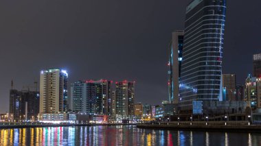 Dubai iş defne gece timelapse kuleleri. Bazı görünüm gökdelenler ve yapım aşamasında yeni kuleleri aydınlatılmış. Kanalı'nın su yansımalar. Köprüdeki trafik