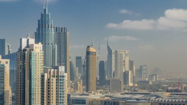 Downtown Dubai şehir silüetinin çatıdan gökdelenler ve kuleleri timelapse ile görüntüleyin. Bulutlar gökyüzü üzerinde