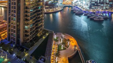 Dubai Yat Limanı içinde en yüksek gökdelenler gece timelapse, Glittering ışıklar ve akşam aydınlatma. Trafik yolda ve mesire avucunda