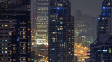 Konut kuleleri aydınlatma ve aydınlatma timelapse ile. Su kanalı ve Dubai Marina manzarası, gece güvertede. Rating gökdelenler ile parlayan pencere eşiği yanında