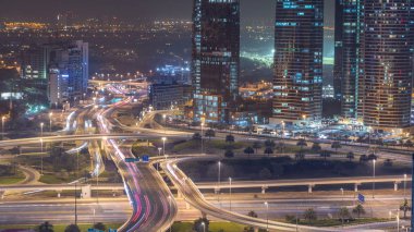 Bir büyük şehir gece timelapse bir yol kavşak hava görünümünü. Arabalar ve gökdelenler ile UAE Dubai Yat Limanı bölgesinin kentsel peyzaj.