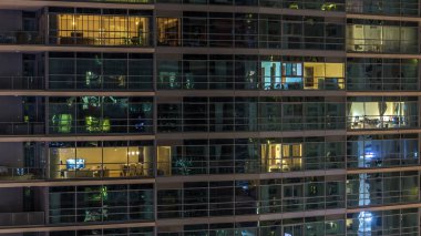 Akşam timelapse, gökdelenlerin parlayan windows. Görünümü office yüksek katlı binalarda Dubai Yat Limanı ve modern konut. İnsanlar hareketli iç. Hava üstten görünüm. Yukarı kaydır