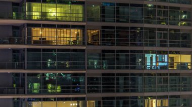 Akşam timelapse, gökdelenlerin parlayan windows. Görünümü office yüksek katlı binalarda Dubai Yat Limanı ve modern konut. İnsanlar hareketli iç. Hava üstten görünüm.