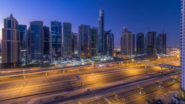 Jumeirah lakes hava görünümünü gün geçiş timelapse Şeyh zayed road ve metro hattı üzerinde trafik ile gecesine ışıklandırılmış gökdelenler ile kuleleri. Dubai Yat Limanı güneş doğmadan önce çatı görünümü