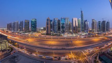 Sheikh zayed road ve metro hattı üzerinde Jumeirah lakes towers gökdelenler gün gece geçiş timelapse trafik için havadan görünümü.