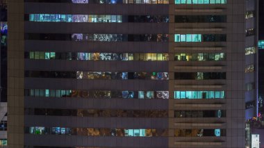 Windows çok katlı binanın içinde aydınlatma ve insanlar timelapse içinde hareketli çelik ve cam. Modern ofis gökdelenler Dubai Hava görünümünü. Yukarı kaydır