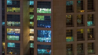Windows çok katlı binanın içinde aydınlatma ve insanlar timelapse içinde hareketli çelik ve cam. Modern ofis gökdelenler Dubai Hava görünümünü. Pan sol