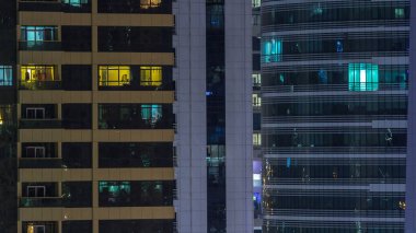 Windows çok katlı binanın içinde aydınlatma ve insanlar timelapse içinde hareketli çelik ve cam. Modern konut ve ofis gökdelenler Dubai havadan görünümü.