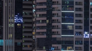 Windows çok katlı binanın içinde aydınlatma ve insanlar timelapse içinde hareketli çelik ve cam. Dubai modern konut gökdelenlerin havadan görünümü. Pan sol