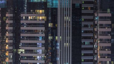 Windows çok katlı binanın içinde aydınlatma ve insanlar timelapse içinde hareketli çelik ve cam. Dubai modern konut gökdelenlerin havadan görünümü.