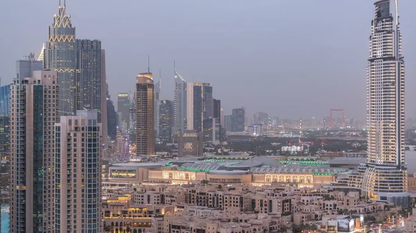 Dobai Downtown day to night transition timelapse. Aerial view over big futuristic city by night. Skyscrapers of Dubai and mall, United Arab Emirates. Evening skyline from rooftop