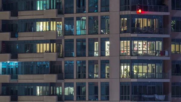 夜のタイムラプスで高層ビルの光る窓 現代住宅とドバイ マリーナで高層オフィスビルのビュー 移動中を人々 します 空中の平面図です 右にスクロールします — ストック写真