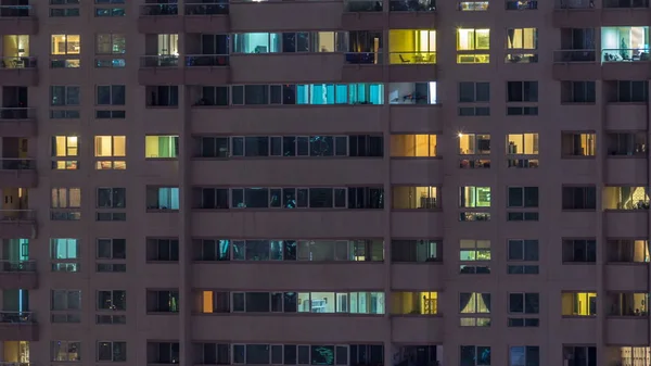 夜のタイムラプスで高層ビルの光る窓 現代住宅とドバイ マリーナで高層オフィスビルのビュー 移動中を人々 します 空中の平面図です 下にパンします — ストック写真